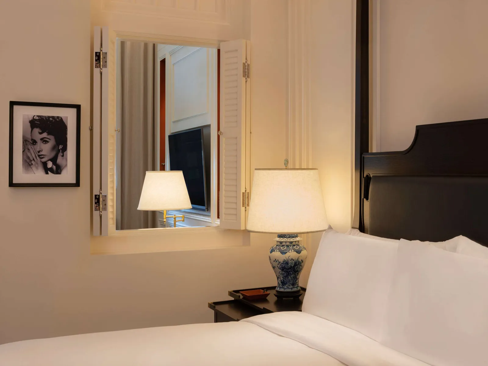 A corner of a Personality Suite: the black-and-white portrait of a woman beside the internal window and the bed.
