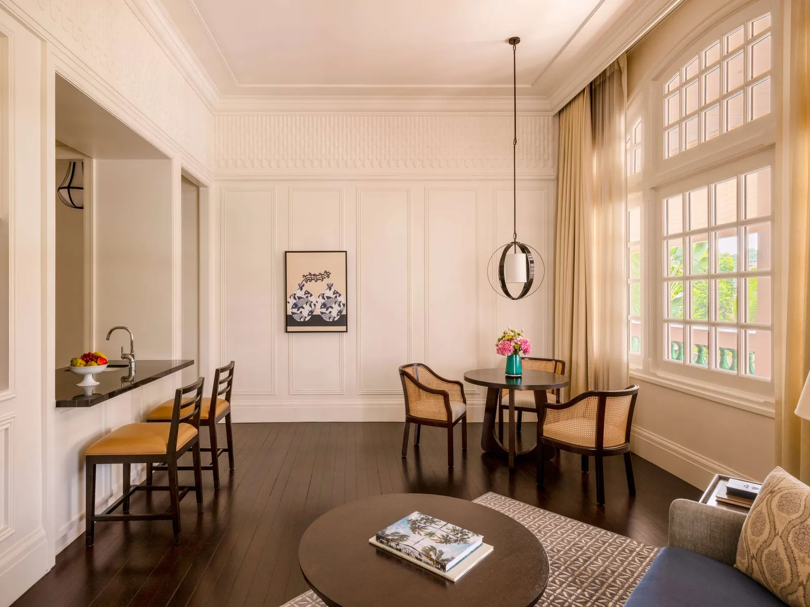 A Residence Suite’s living room: the kitchenette counter with its stools, the round table and tall windows.