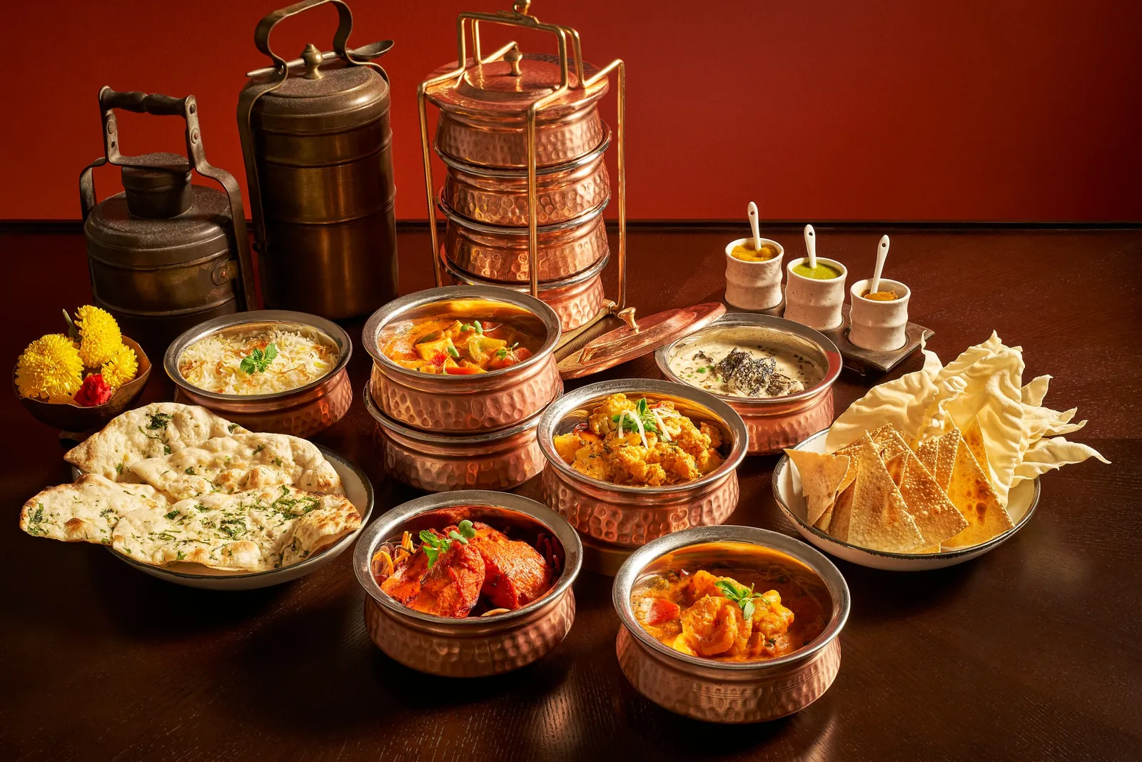 Tiffin Room’s curries in copper bowls, with naan, poppadoms and the stacked copper tiffin boxes.