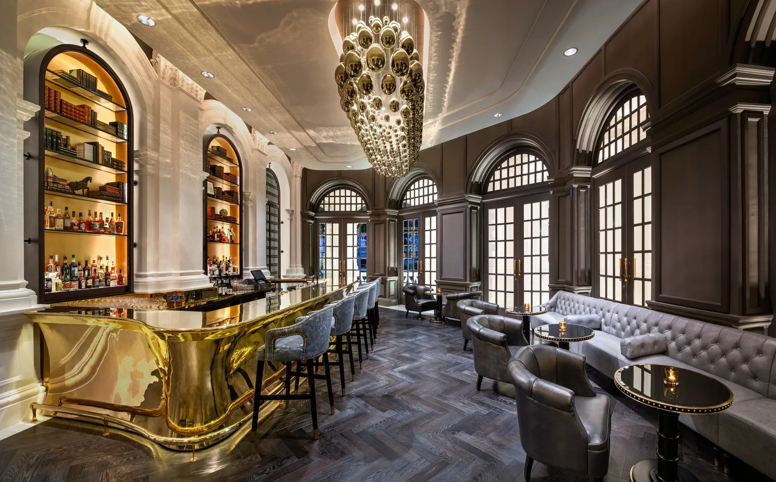 Writers Bar: the gilded counter, arched niches lined with bottles, grey leather banquettes and a chandelier of overlapping scales.