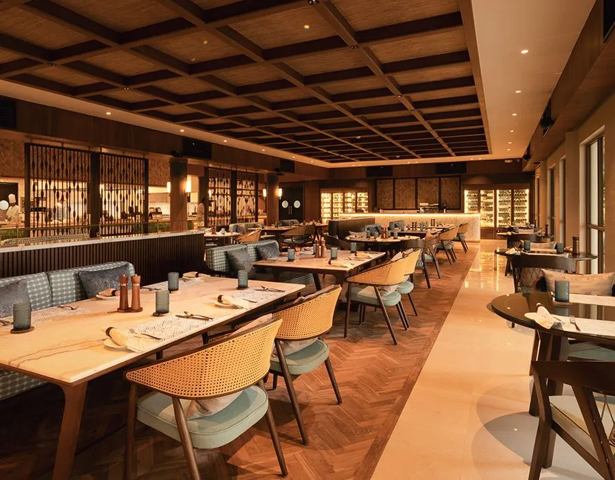Juliette’s dining room, with pale wooden tables, upholstered chairs and a coffered ceiling.