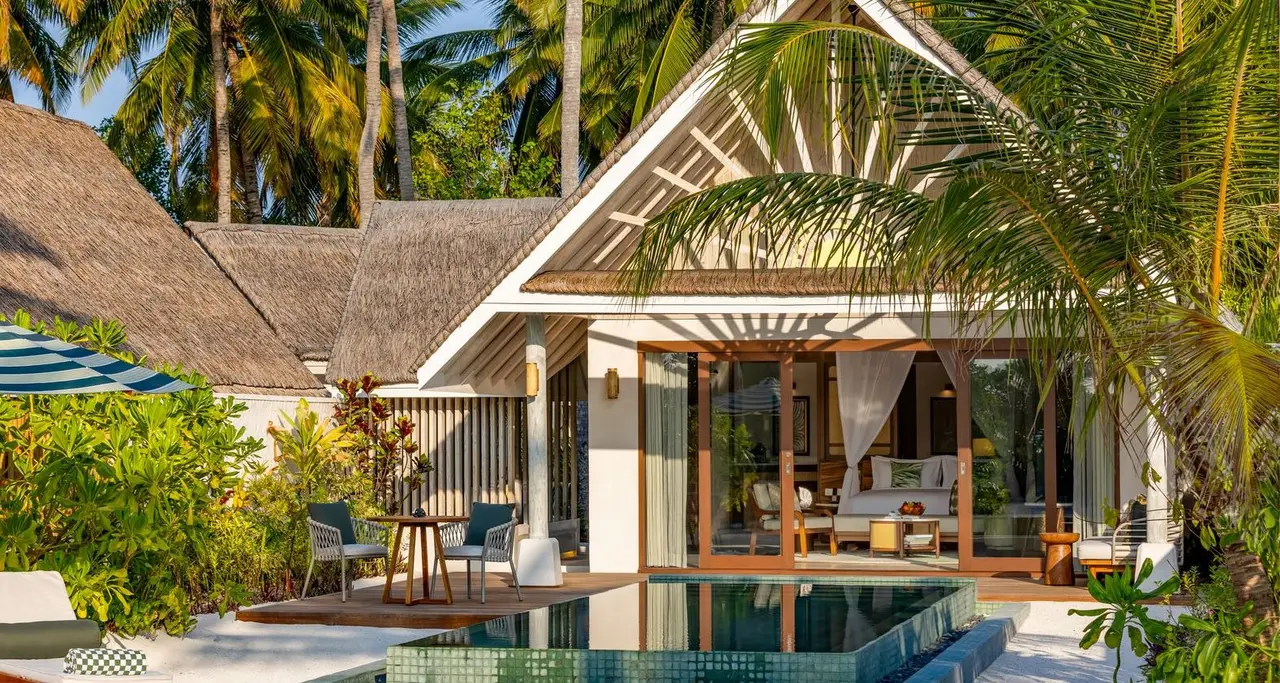 A Sunset Beach Pool Villa by day, with its terrace, loungers and pool between the lawn and the palms.