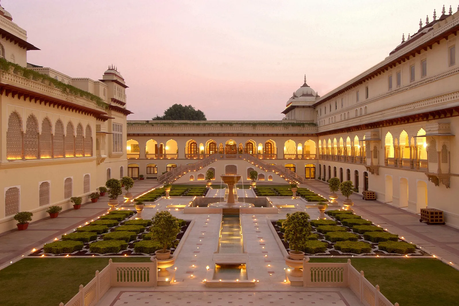 Rambagh Palace’s Mughal garden at dusk, between lit arcades