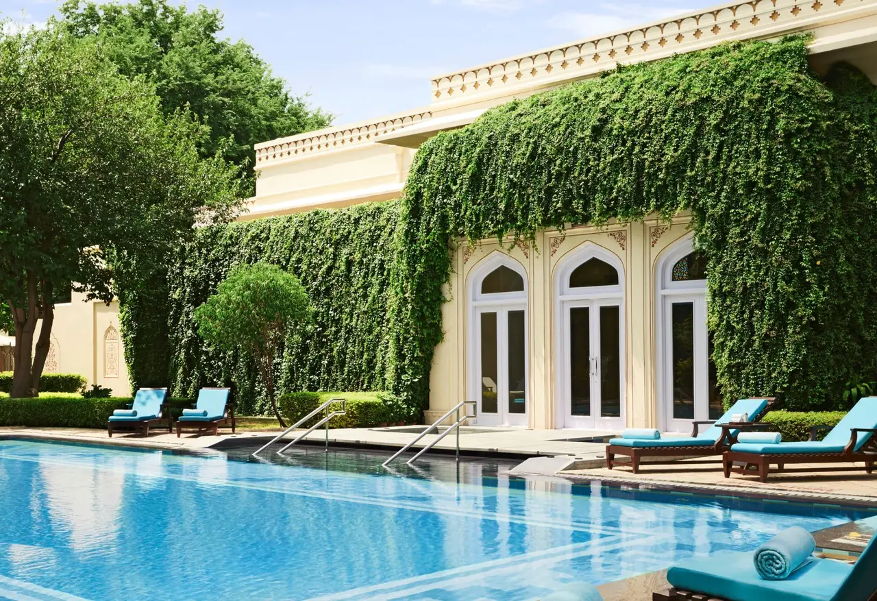 The outdoor pool in front of an ivy-covered façade, with turquoise loungers