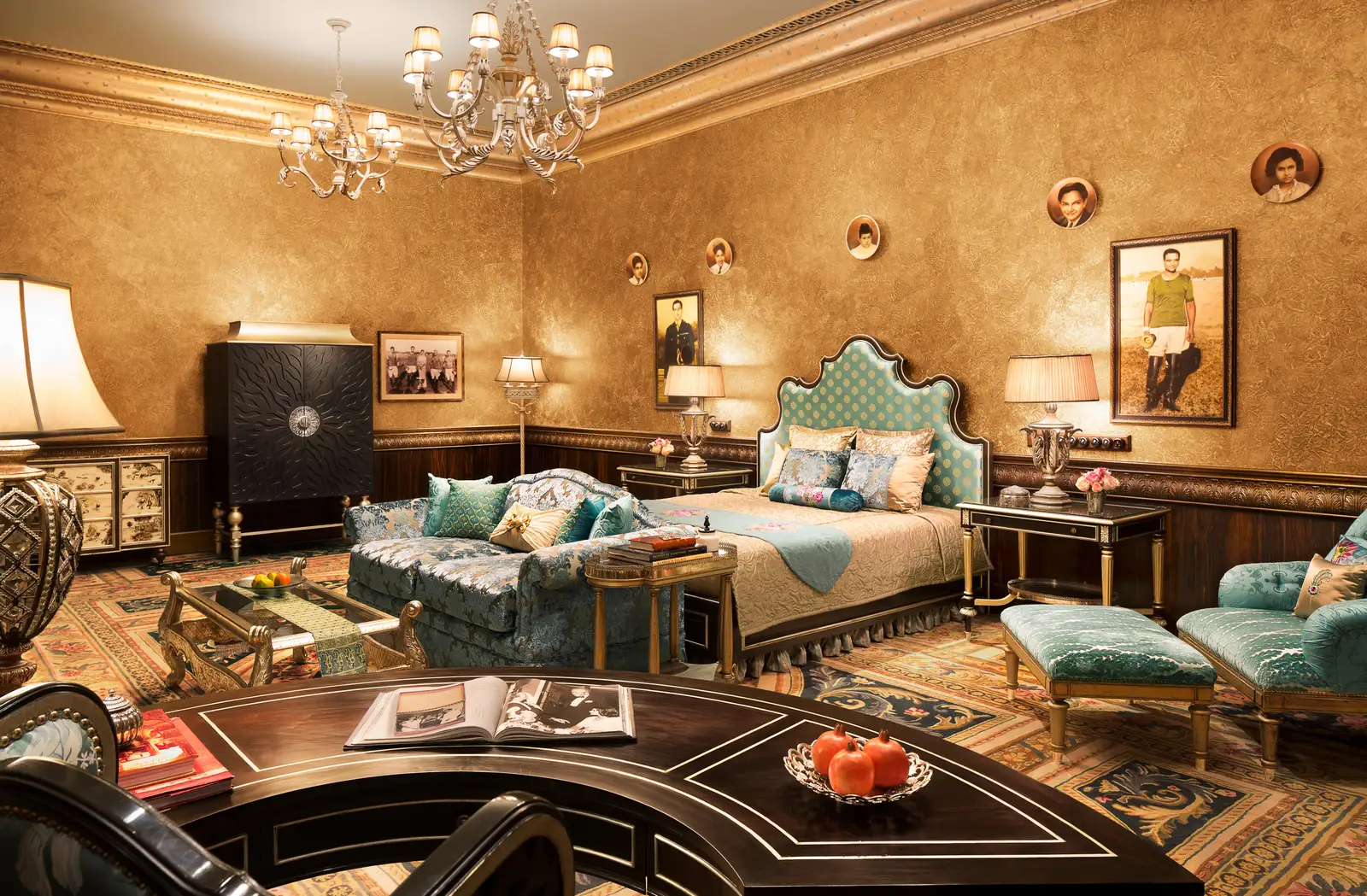 A Royal Suite with a teal sofa, bed and portraits on gilded walls