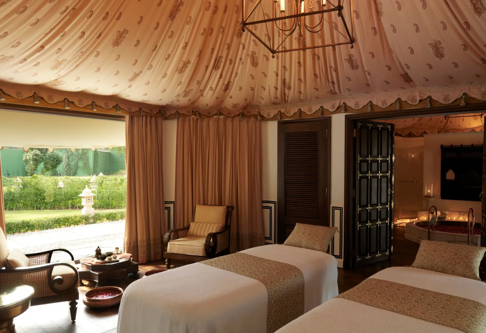 A spa treatment room under canvas, with 2 beds and the garden beyond the glass