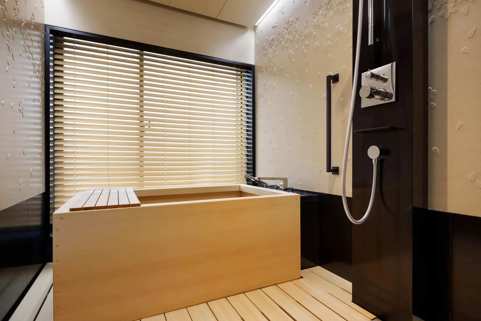 A square hinoki-wood tub with its lid, the hand shower and a slatted wooden floor.