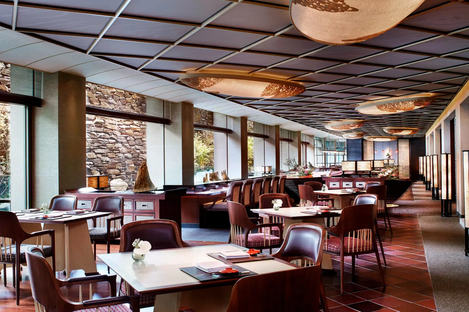 Mizuki’s dining room: laid tables, the counter at the back, the coffered ceiling and a dry-stone wall beyond the windows.