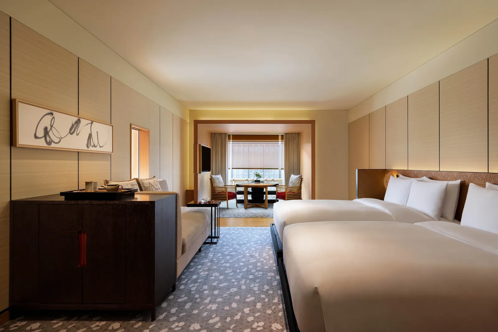 A Deluxe Kyoto room with 2 beds, the dark sideboard, the sofa and the bamboo-blinded window at the far end.