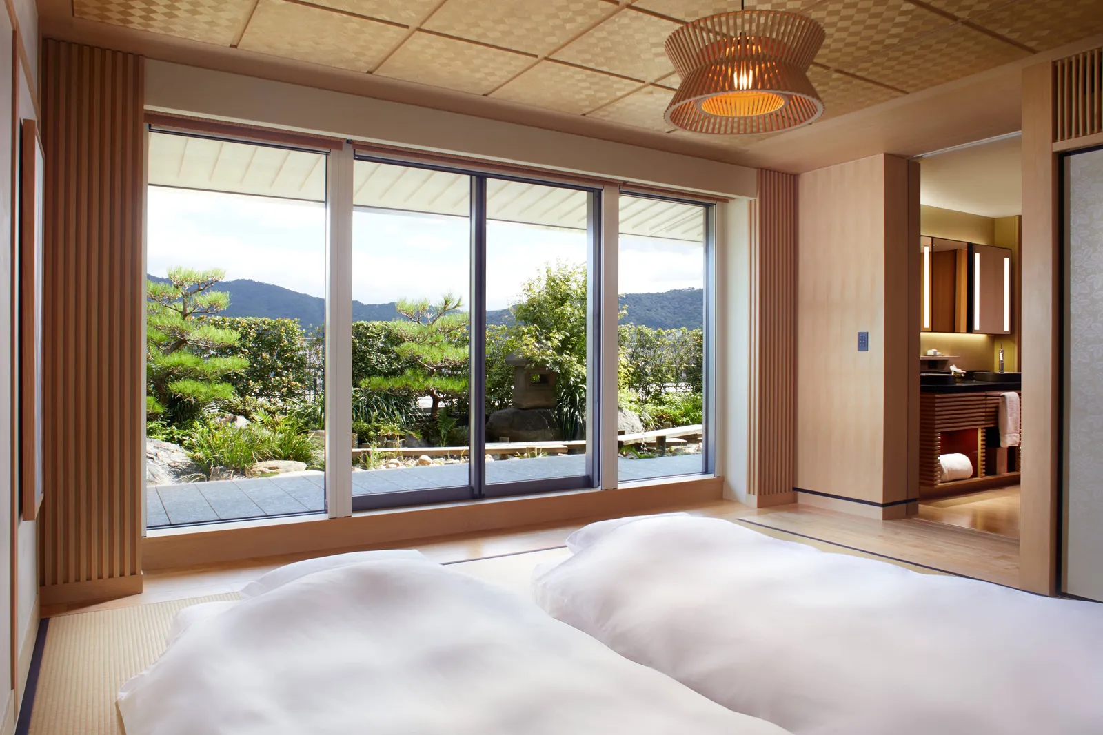 2 futons on the tatami of a Garden Terrace TATAMI suite, facing the windows onto a garden of pines and the mountains.