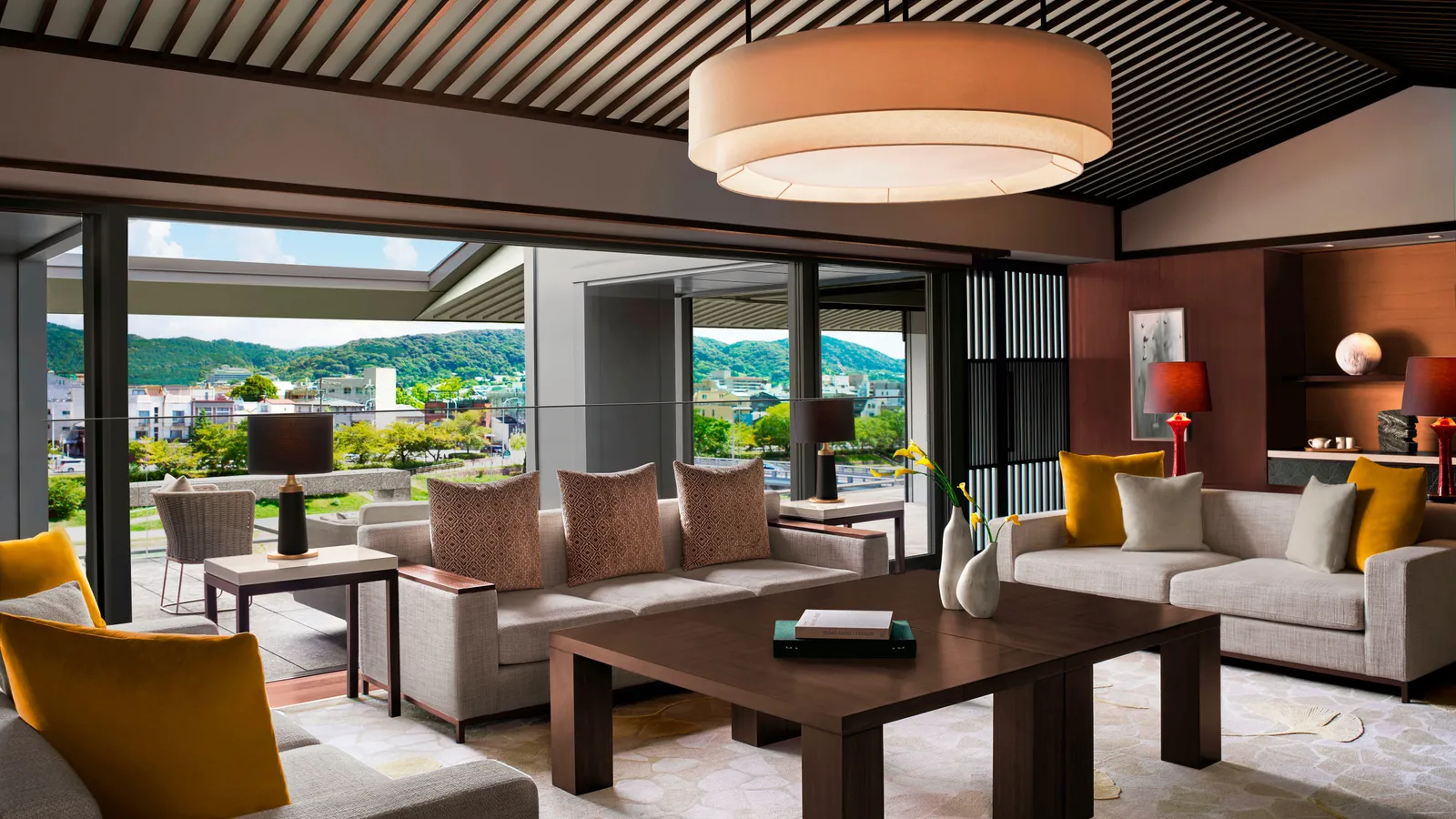 The Ritz-Carlton Suite’s drawing room, with 2 sofas, yellow cushions and the terrace open to the river and the hills.