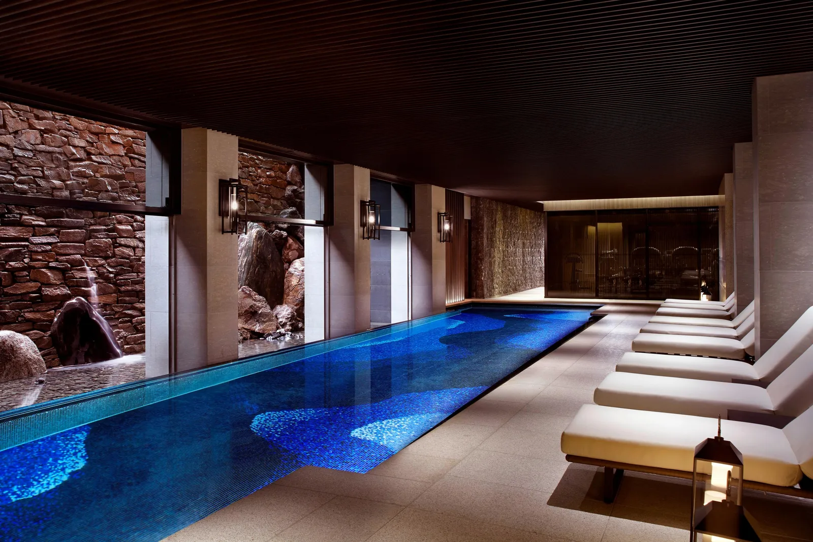 The 20-metre indoor pool, with its blue mosaic, a row of white loungers and the water falling down the stone wall.