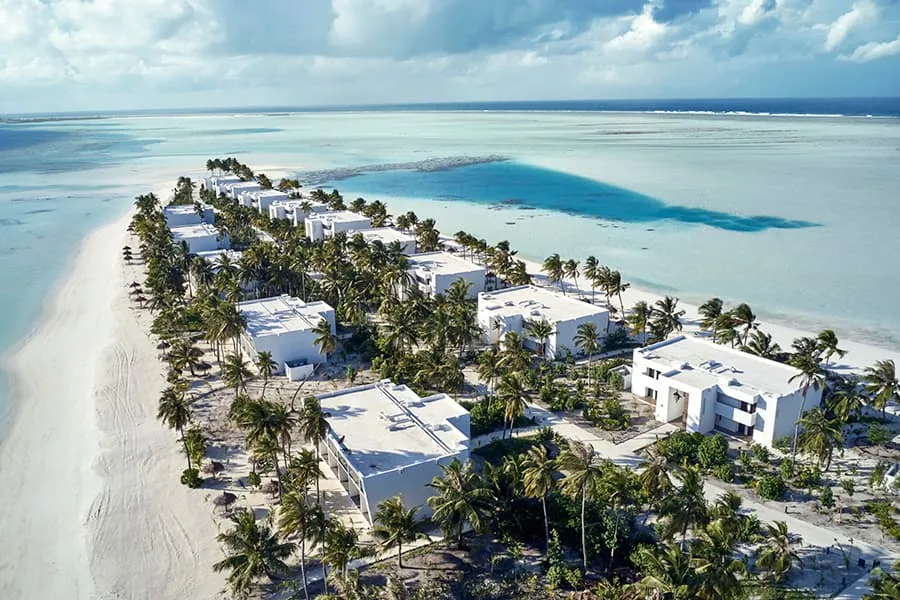The white room buildings among the palms, seen from above, with the lagoon on both sides.