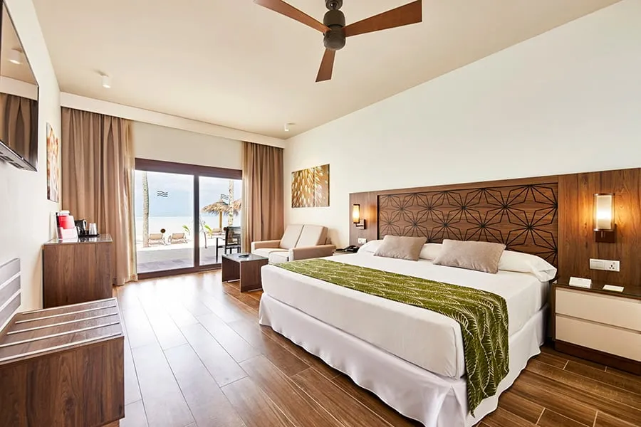 The room with direct beach access, its king bed and the door open to the patio and the sea.