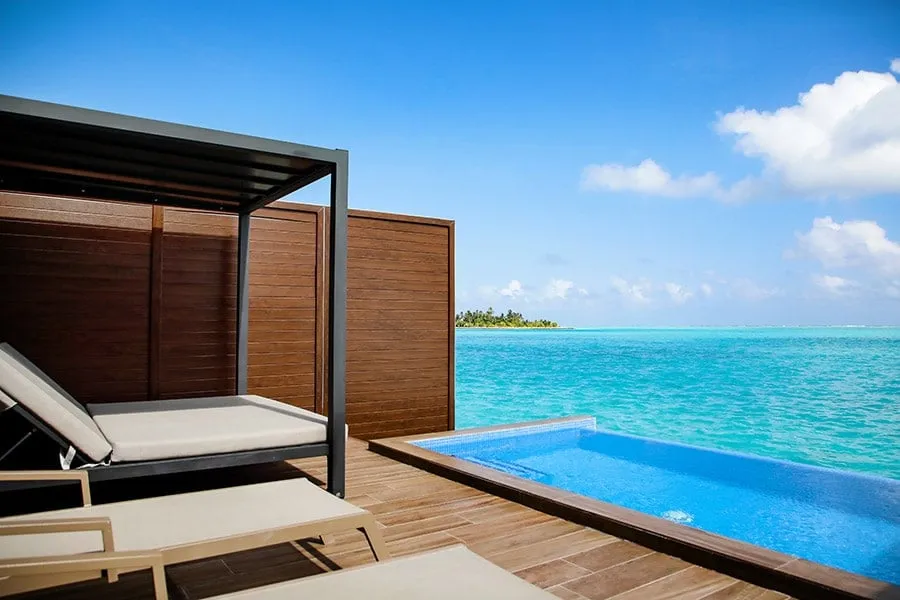 The deck of an overwater Suite with private pool: the small pool, the Balinese bed under its canopy and the lagoon.