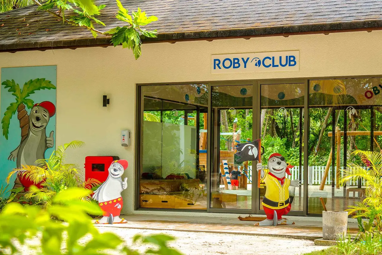 The entrance to the ROBY CLUB, with its glass front, painted walls and tropical plants outside.
