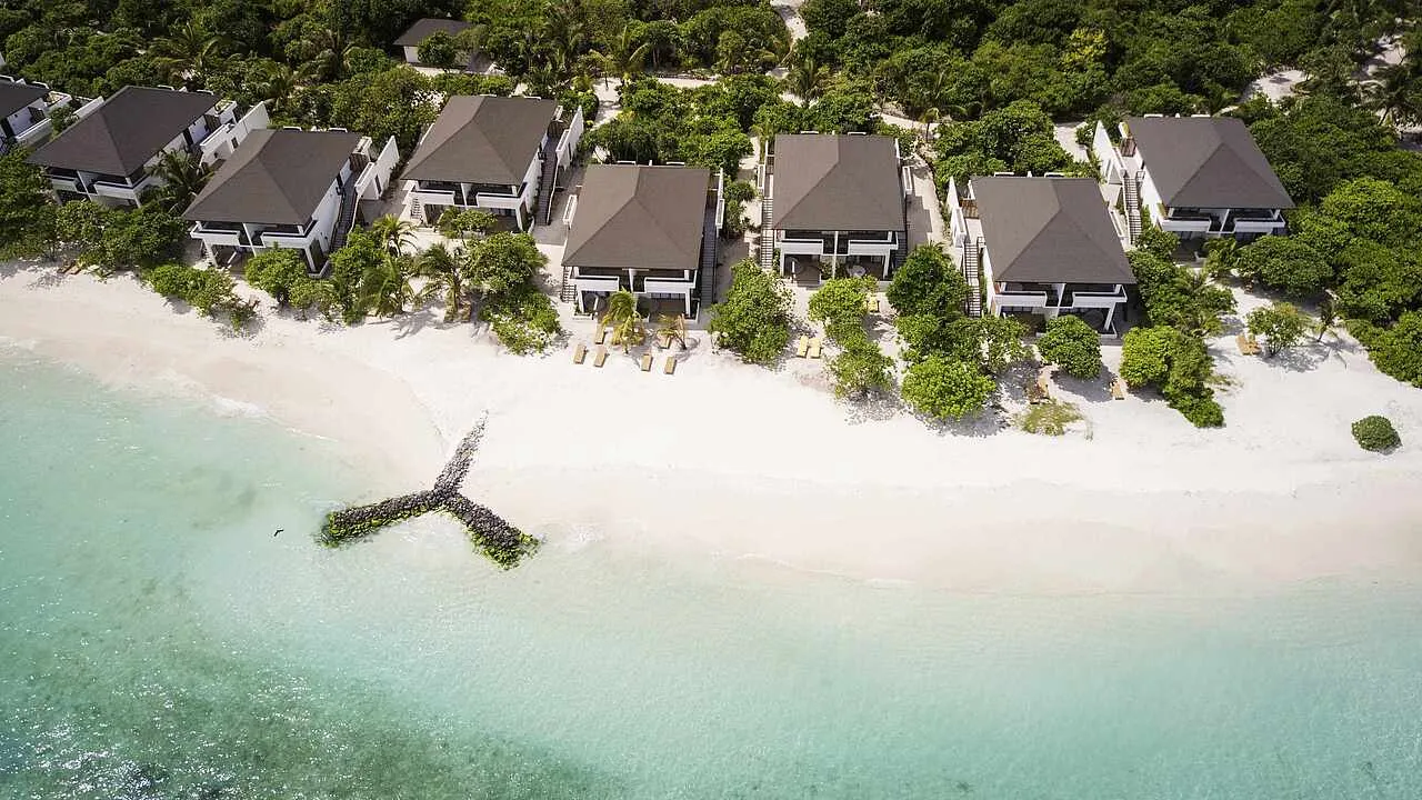 The 2-storey blocks of double rooms among the palms, seen from above over the beach and the pale lagoon.