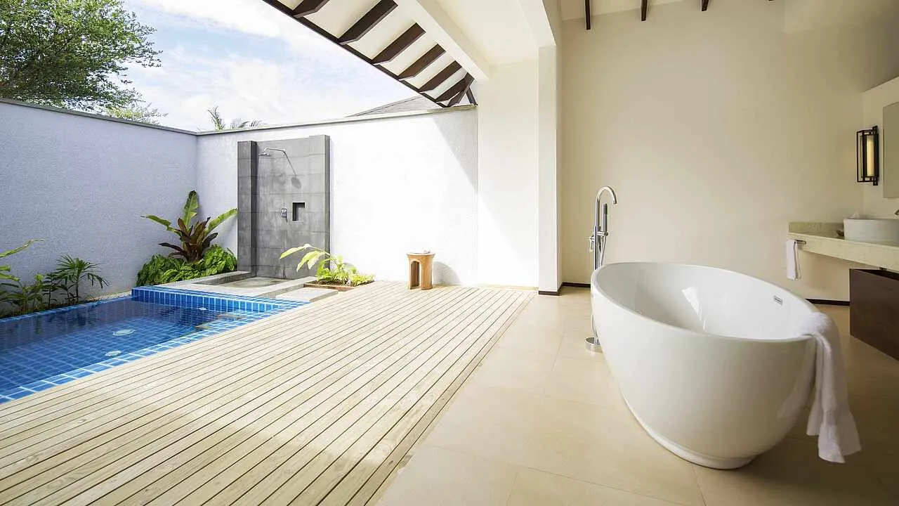 The open-air bathroom of a Villa Economy: the freestanding bath on the decking, the stone shower and the small private pool among the plants.