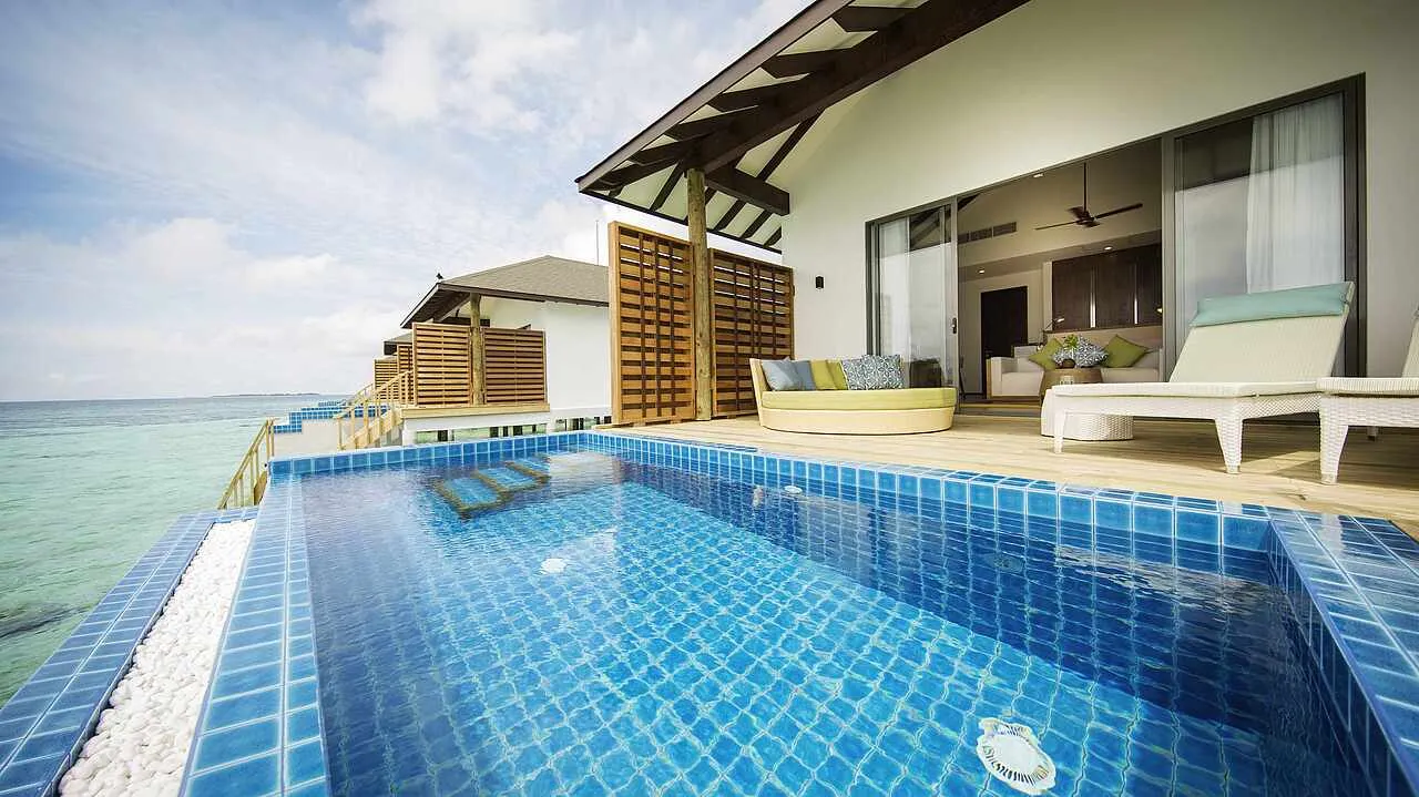 The deck of a Water Villa Sunset View with its blue-tiled private pool, the loungers and the open sea on the sunset side.
