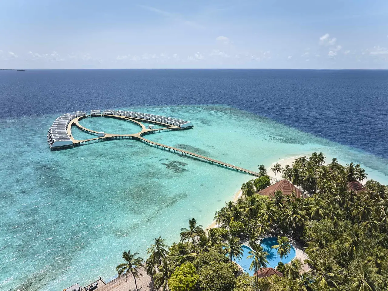 Funamadua from above: the green island with its pool among the palms, the white beach and the jetty out to the ring of water villas.