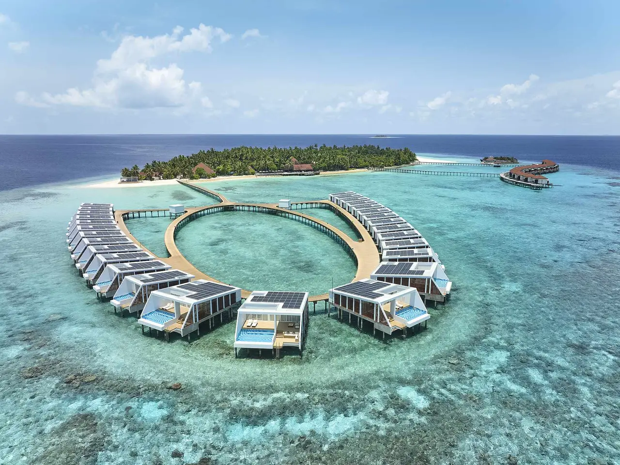 The water villas set in a ring over the lagoon, with their timber walkways and the island in the background.
