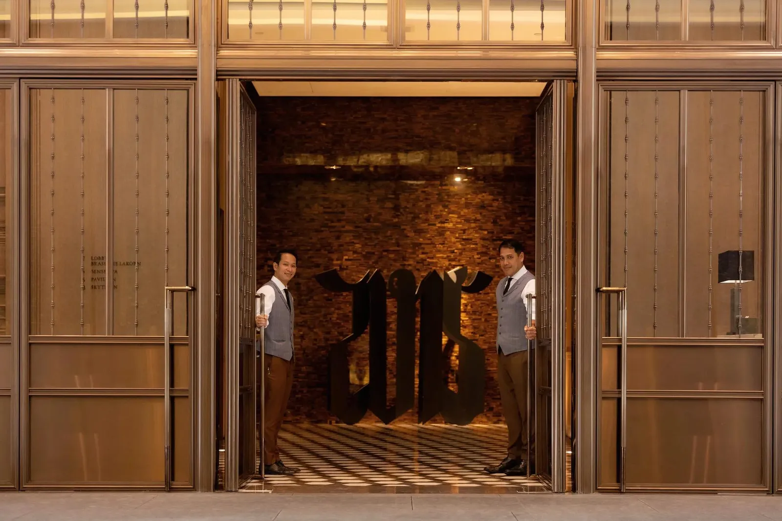 2 portieri aprono le grandi porte di legno dell’ingresso