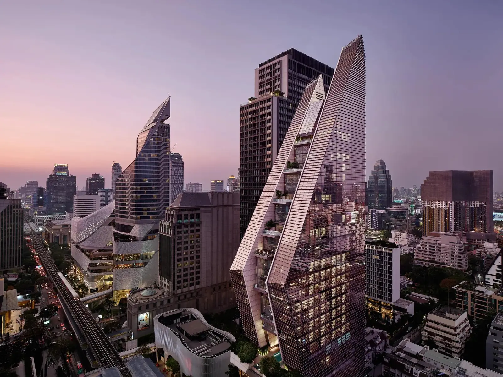 La torre di Rosewood Bangkok, la cui forma si ispira al wai, fra i grattacieli di Ploenchit al tramonto