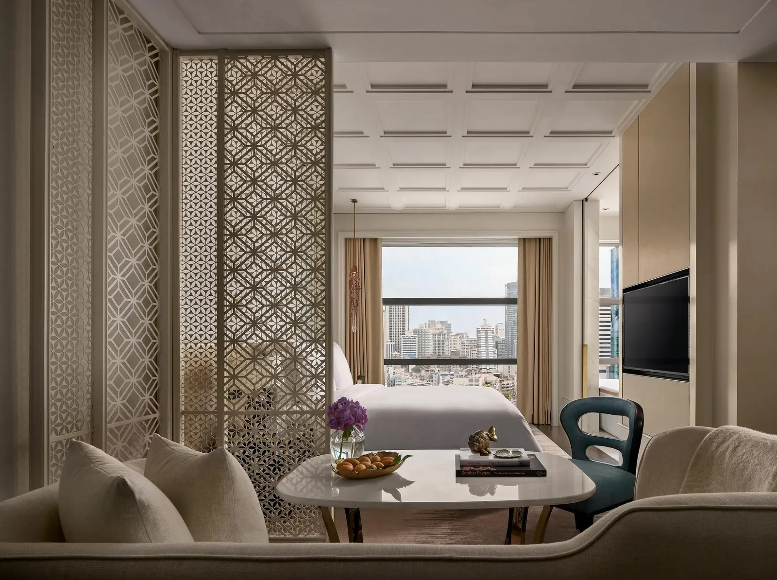 Executive Room: il letto oltre un paravento di legno traforato, con la città nella finestra