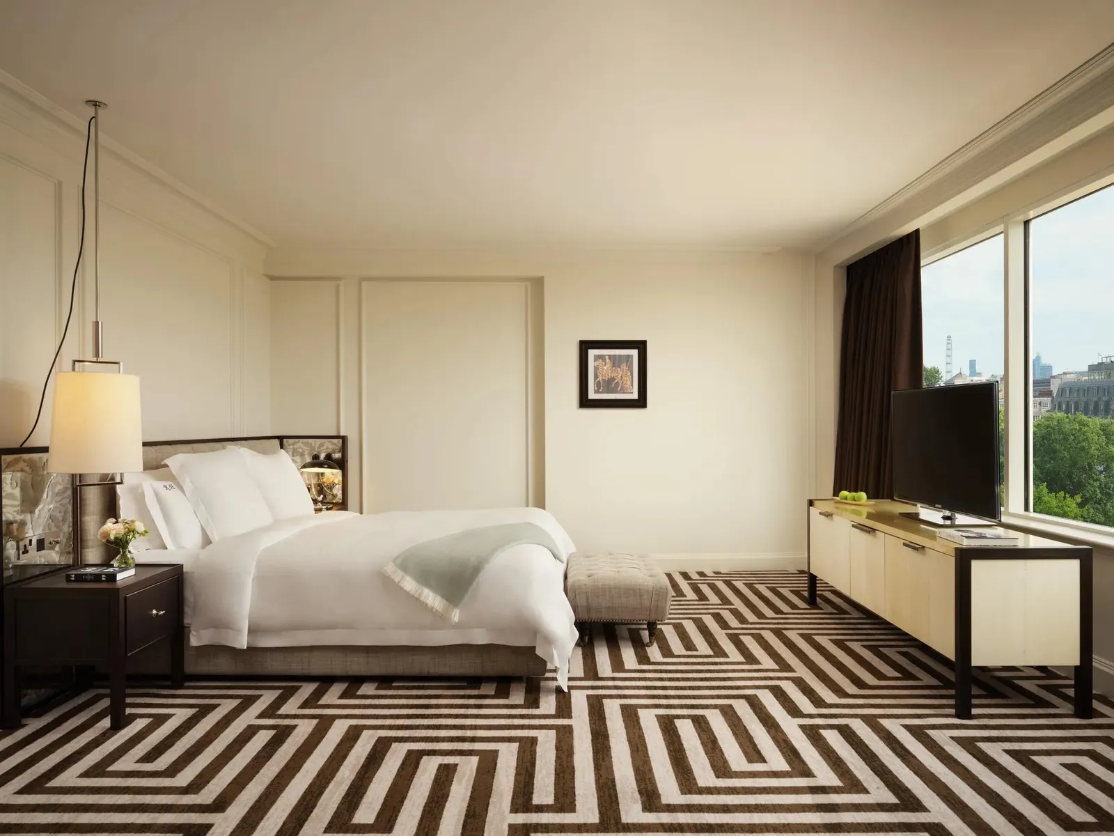 A Junior Suite: a white bed, an armchair, a television and a window onto the trees