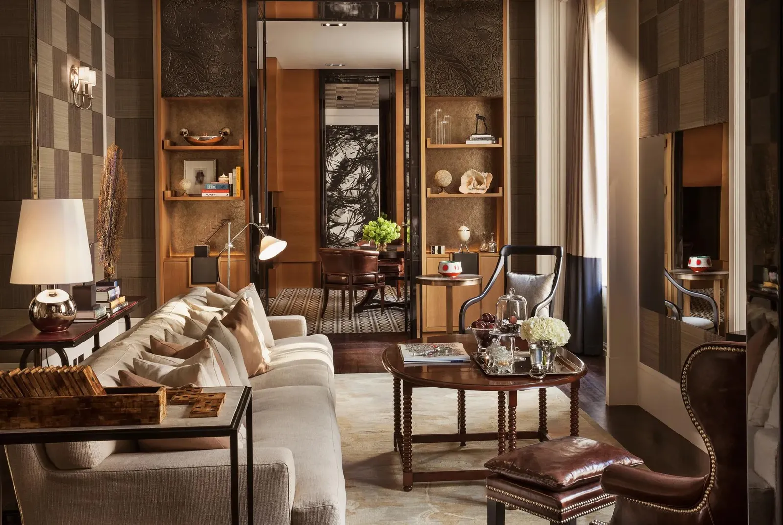 The Manor House sitting room: wooden bookshelves, a pale sofa, leather armchairs and a table lamp