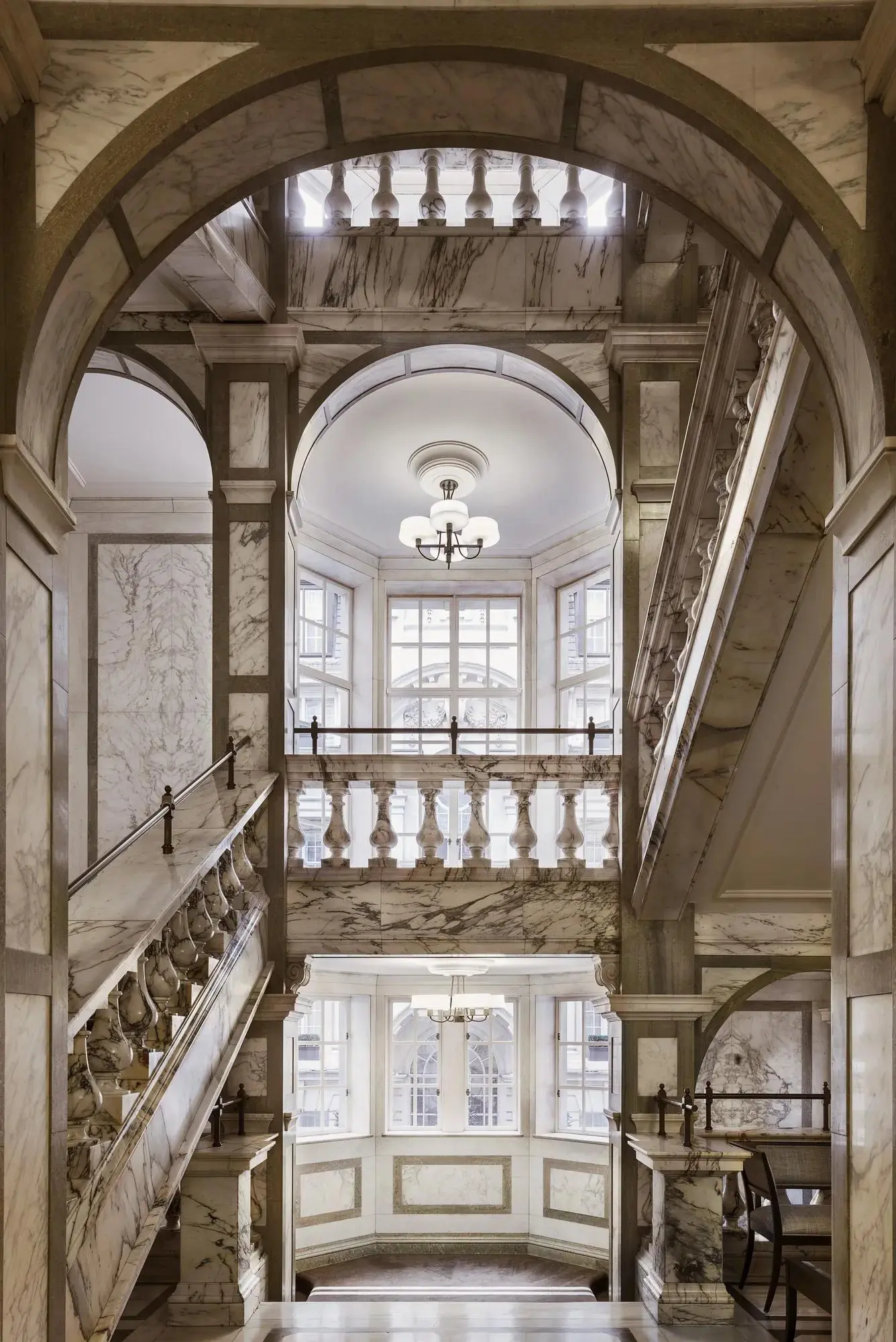 Rosewood London’s marble staircase, its white balustrades rising towards a skylight