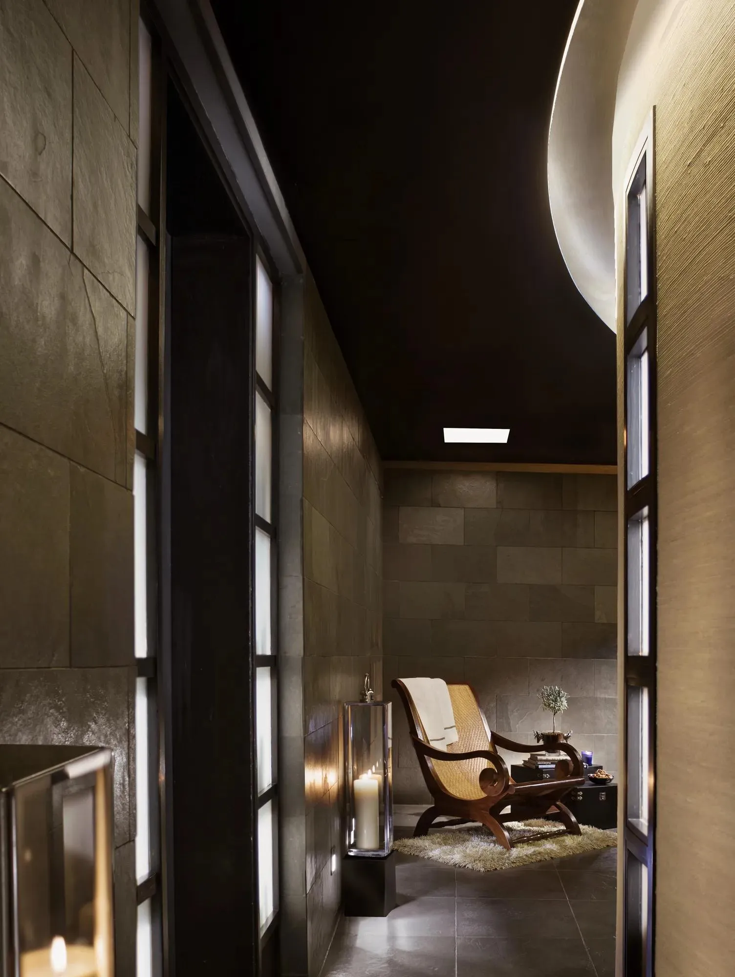 A corridor at Sense spa: dark stone walls, low light and a chaise longue at the end