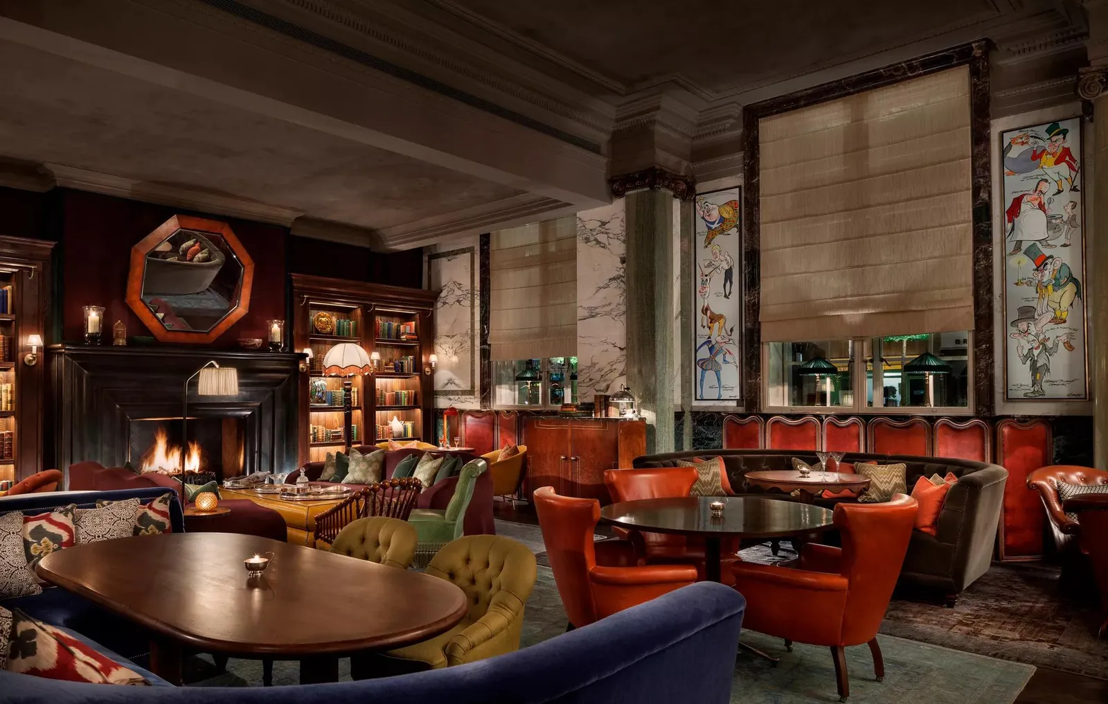 Scarfes Bar’s fireplace room: red armchairs, wooden tables, bookshelves and a lit fire