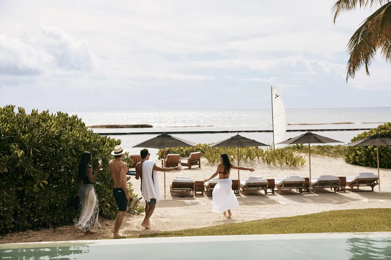 Guests on the sand in front of the suite, among parasols