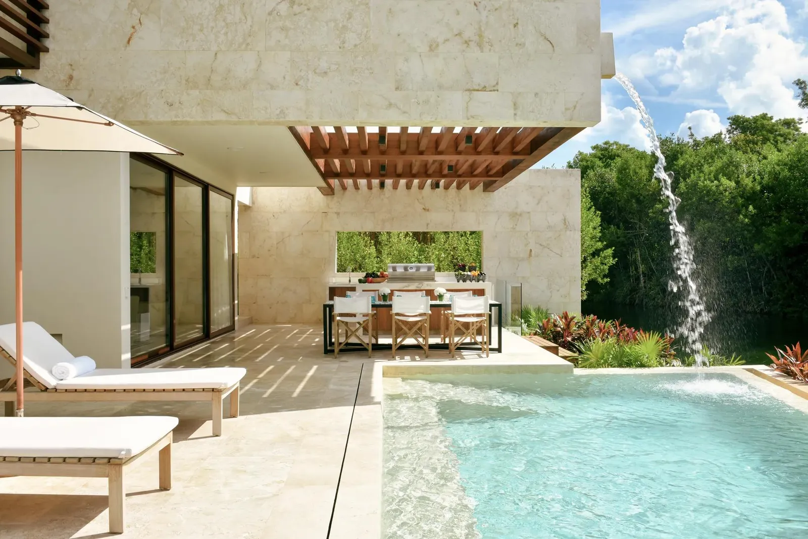 Outdoor dining under the pergola, a waterfall into the pool