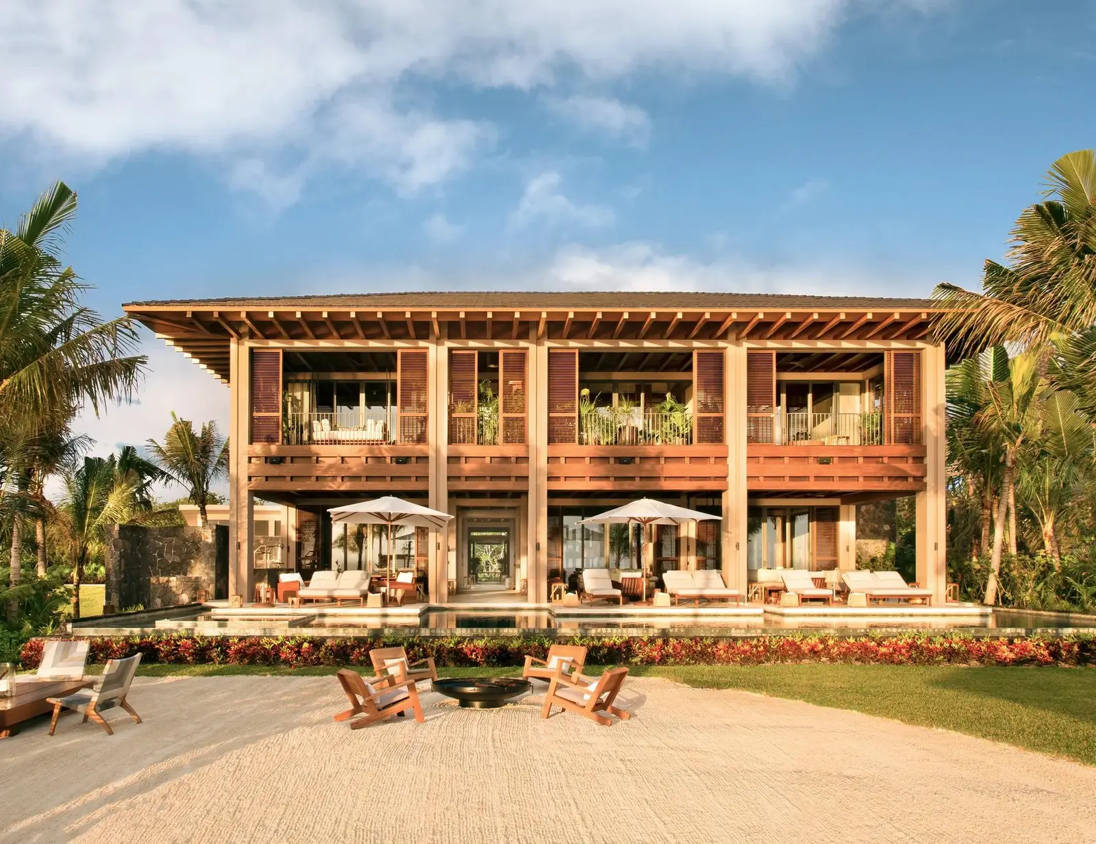 The villa’s timber façade on the beach, loungers in front
