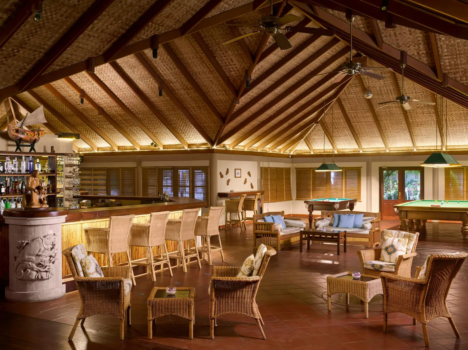 The Fun Pub under its great timber roof: the bar, the wicker armchairs and the billiard tables.
