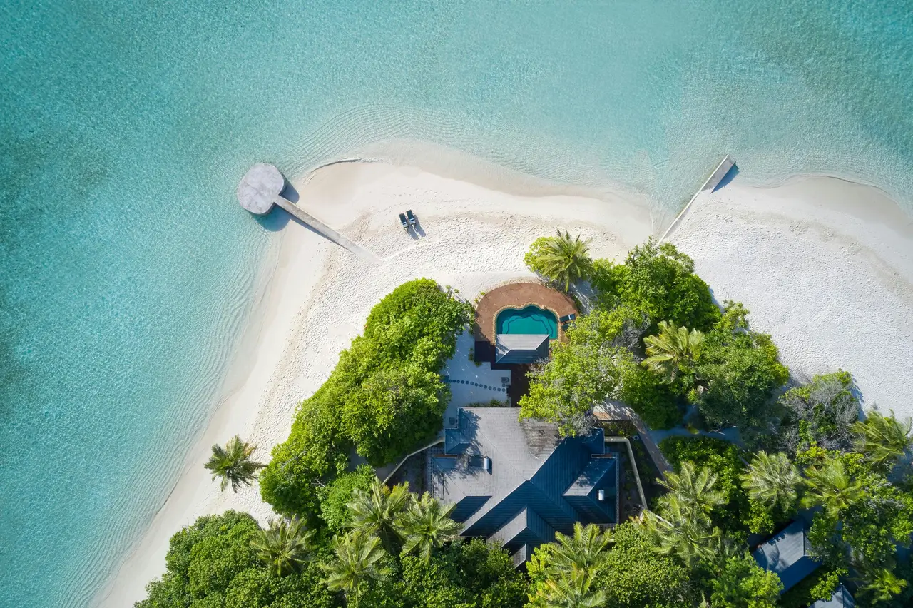 One of the 2 residences from above, at the tip of the island, its pool among the palms, the beach and a jetty.