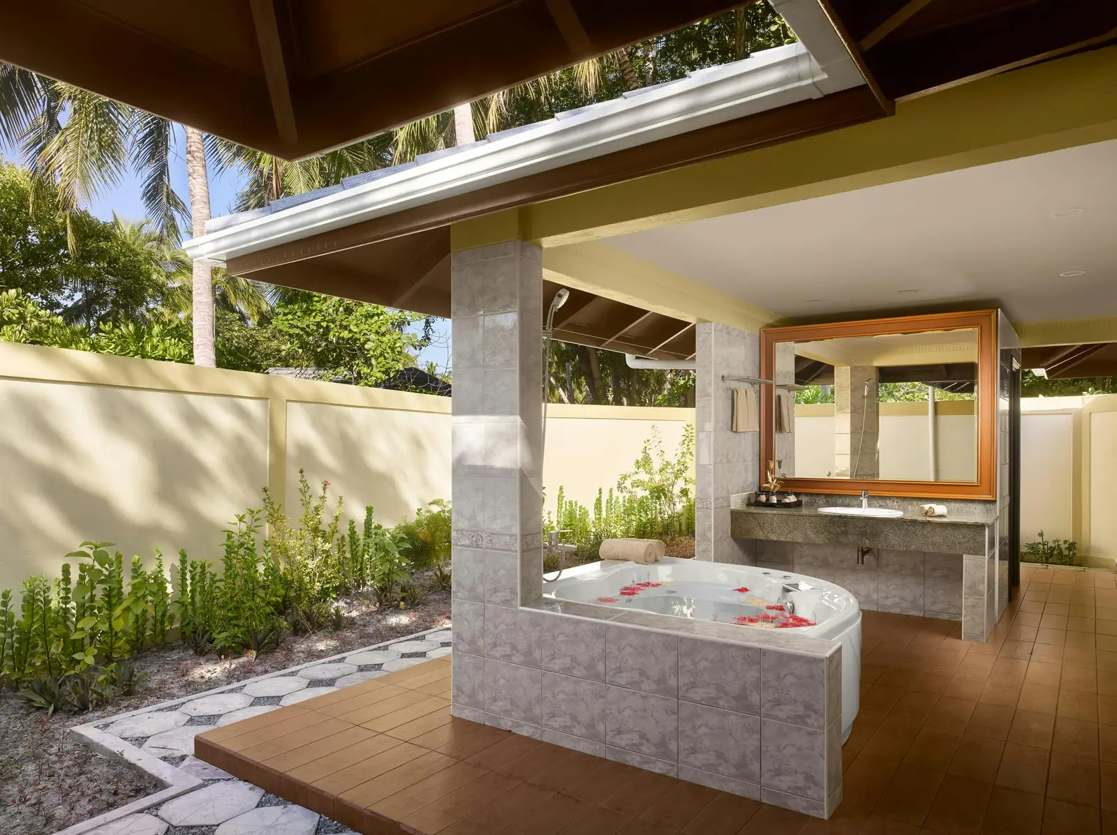 A Two-bedroom Beach Pool Residence’s open-air bathroom, with its whirlpool tub, flowers and the garden.
