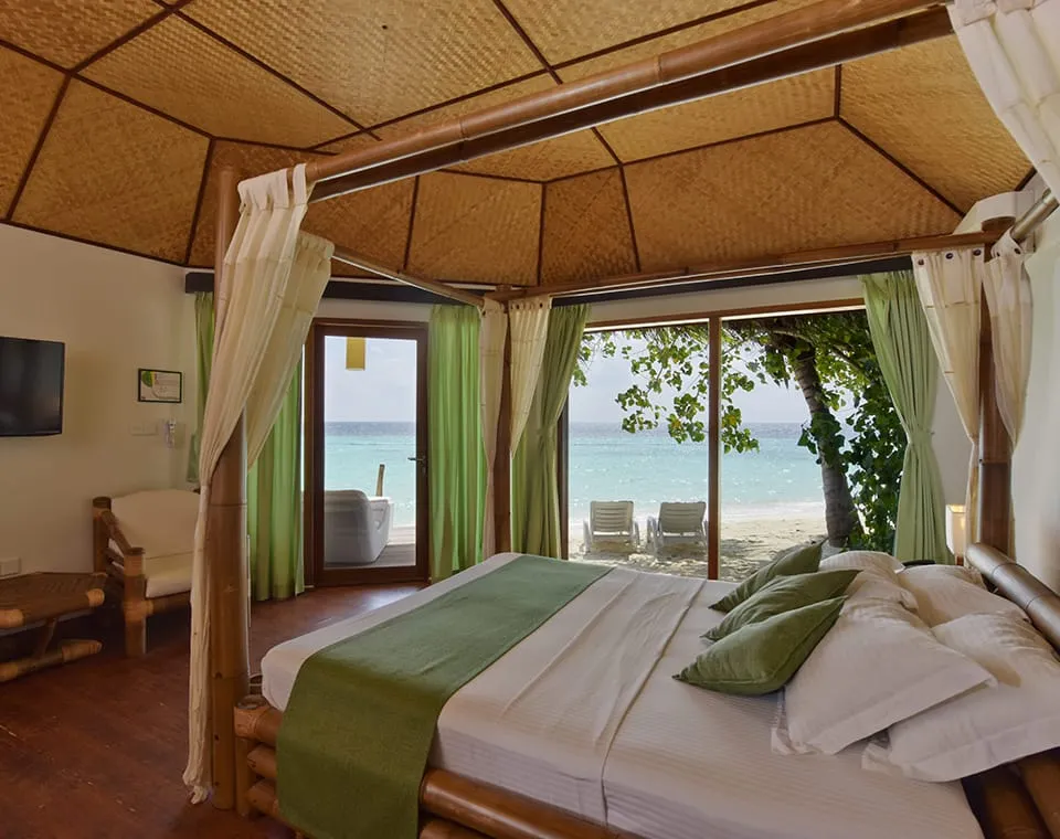 The bedroom with its four-poster bed and doors towards the beach.