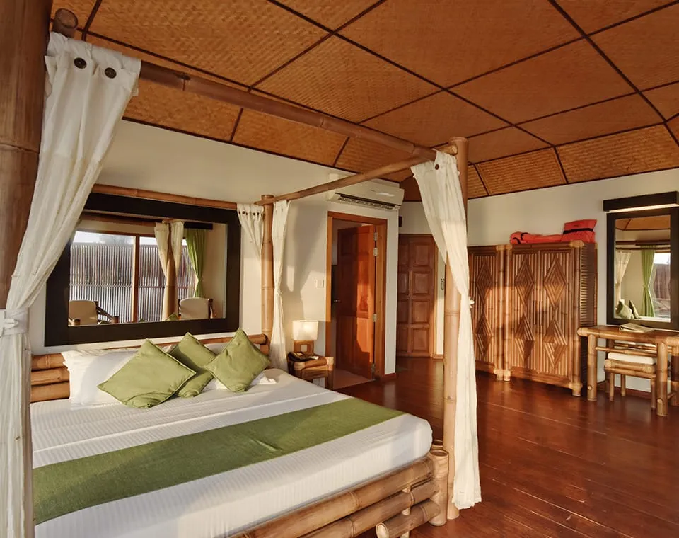 The bedroom with its four-poster bed, wooden doors and bamboo furniture.