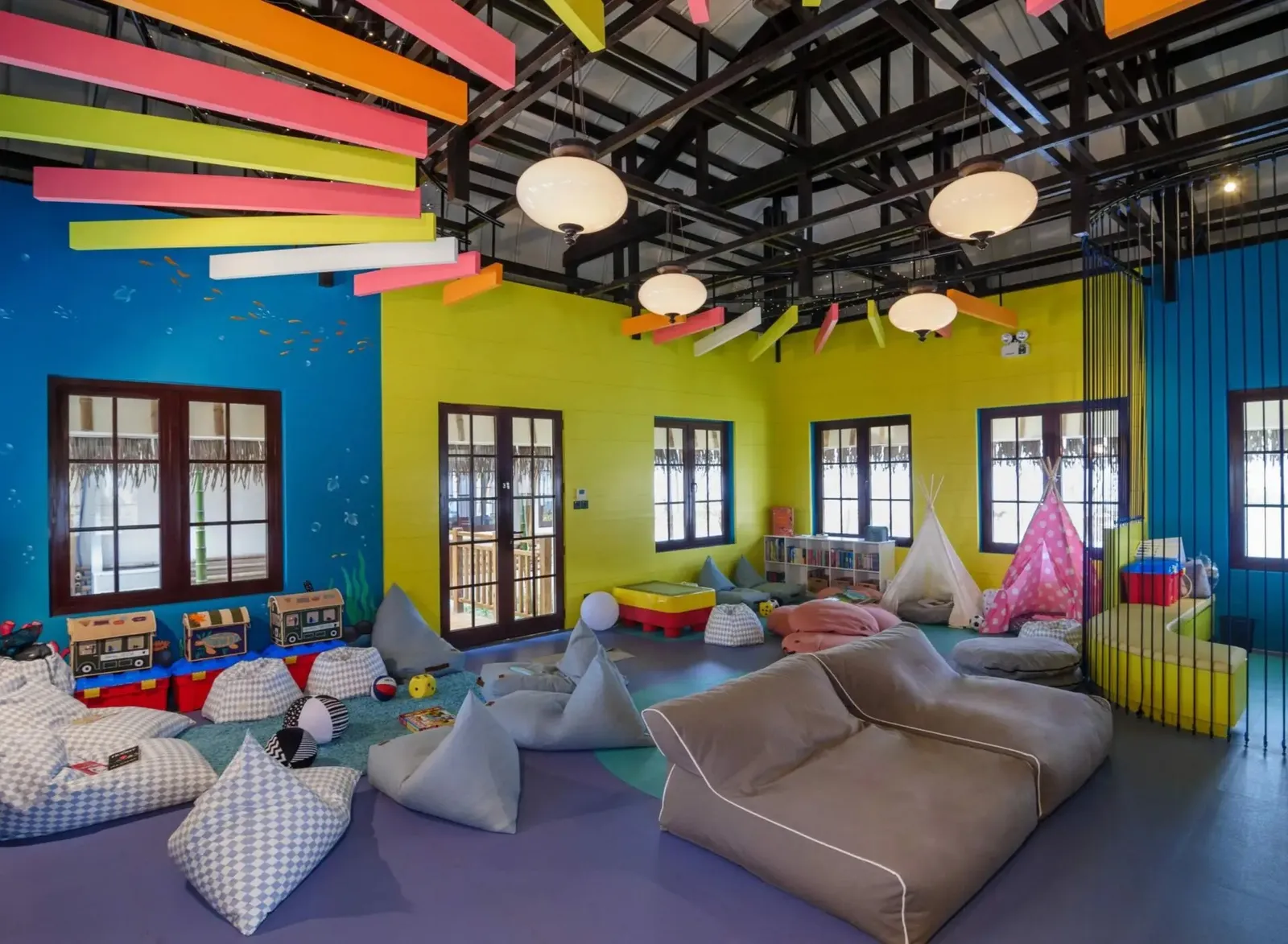 The Junior Beach Club room: yellow and blue walls, beanbags and play tents for the children