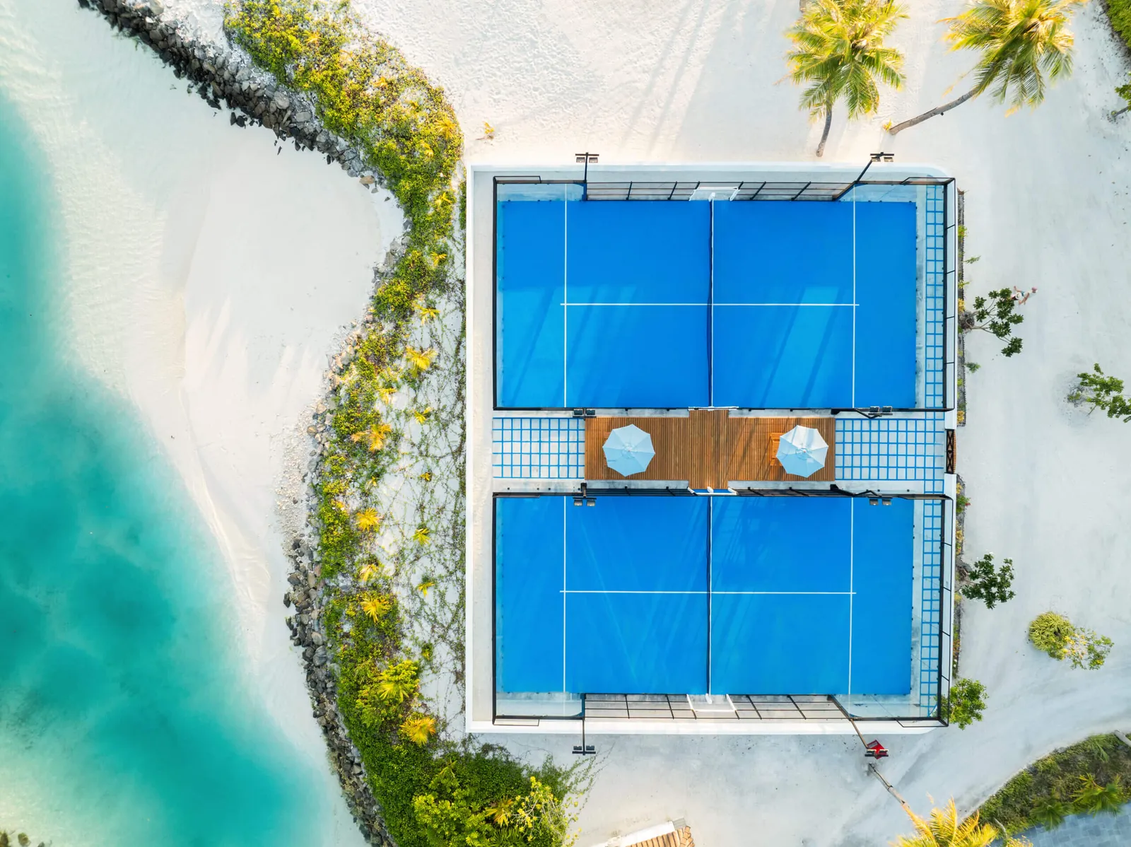 The 2 padel courts seen from above, between the sand and the palms