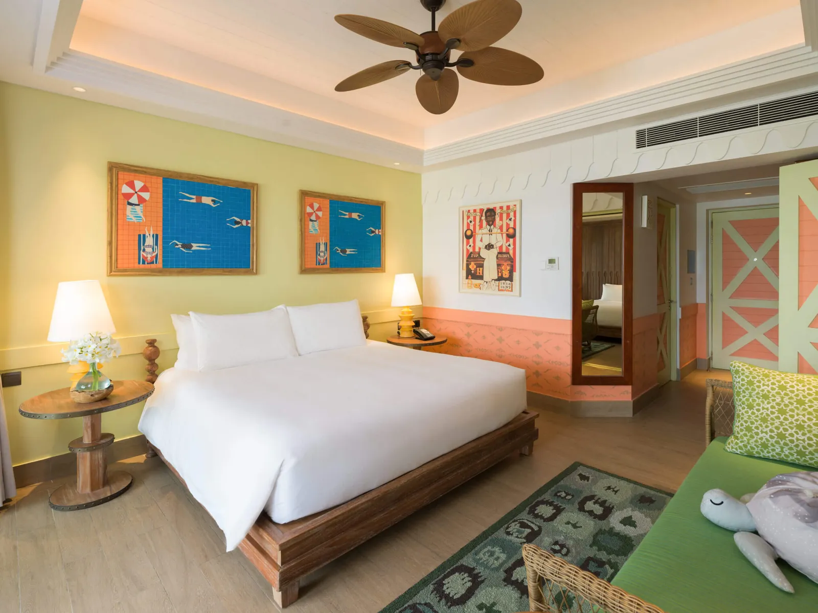 A bedroom in the 2-Bedroom Family Beach Room, bright pictures and a ceiling fan