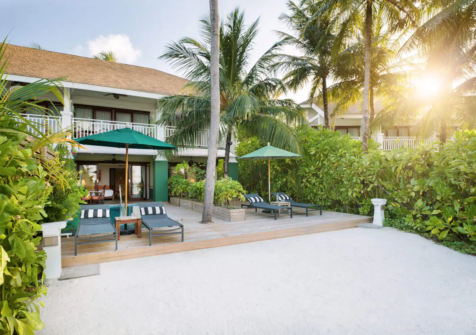 The wooden deck of the 2-Bedroom Family Beach Room with Pool, loungers and sand in front
