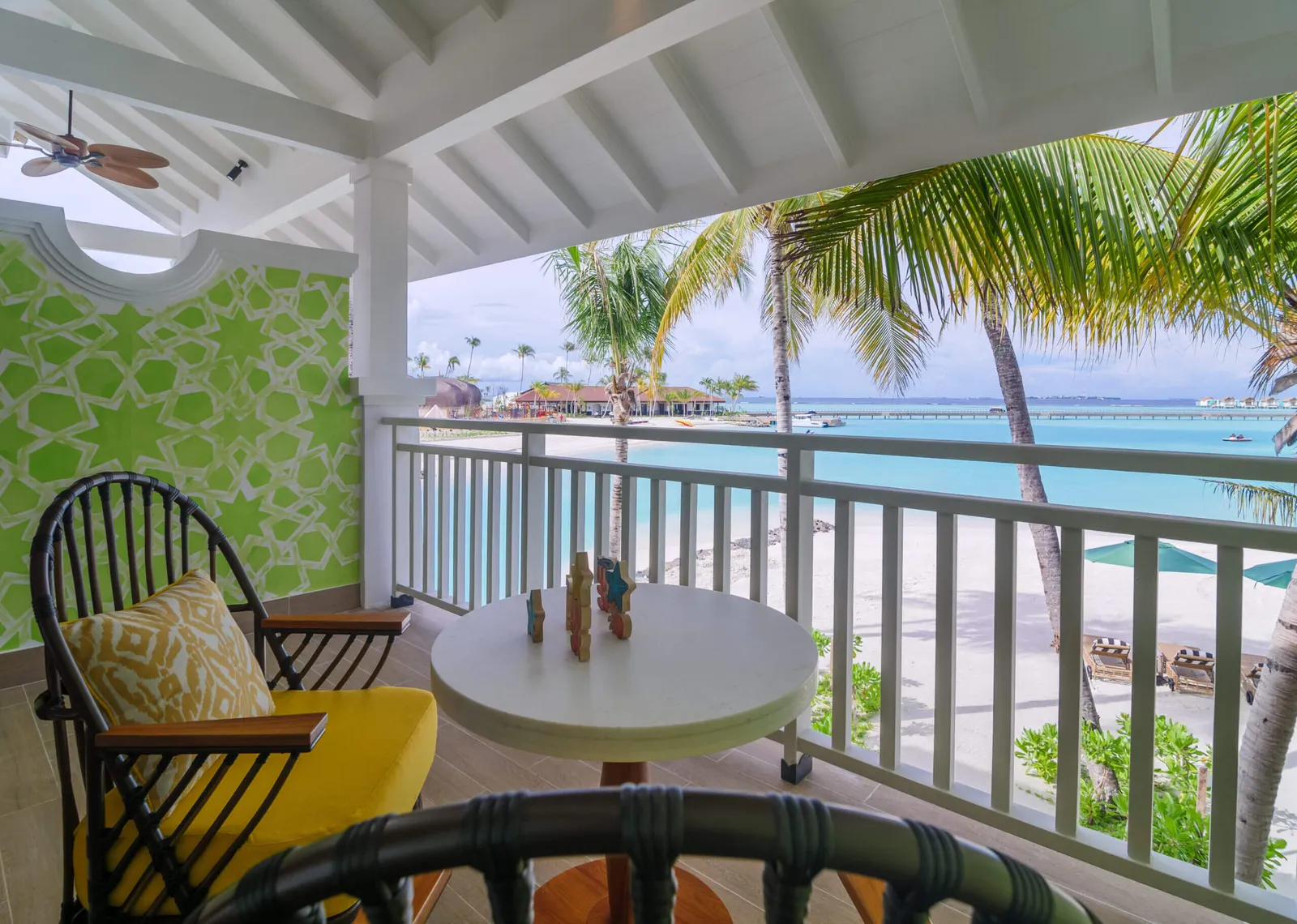 A first-floor Sky Room balcony, its small table and the beach below the palms