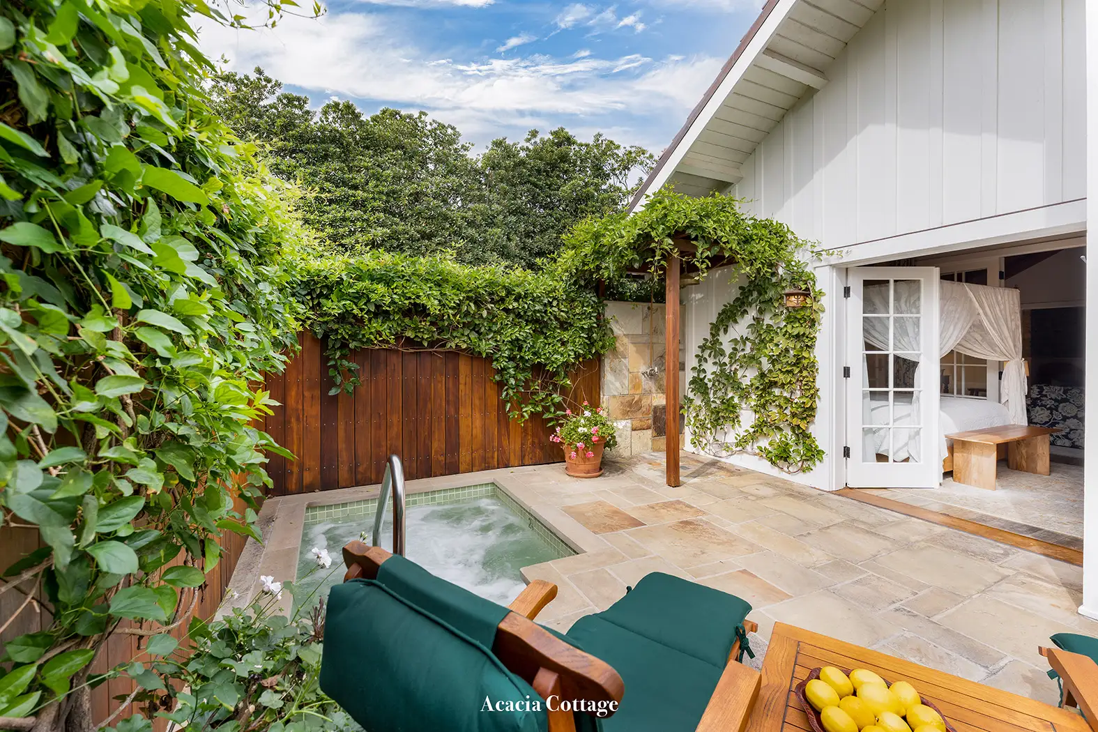 Acacia: the paved patio with its sunken spa, green loungers and French doors open to the bedroom.