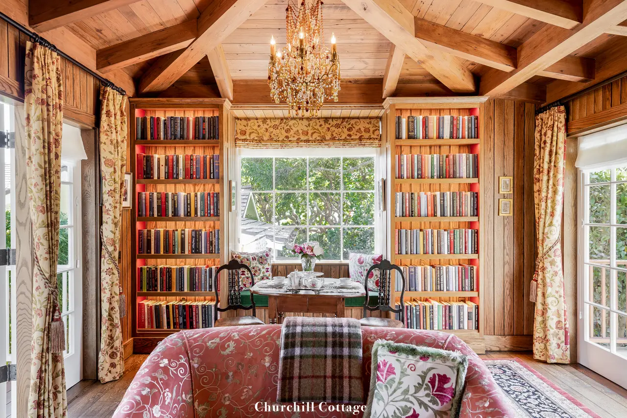 Churchill: the wood-panelled living room, bookcases either side of the window, a crystal chandelier and a pink sofa.