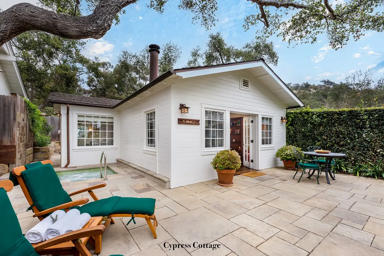 Cypress: the white cottage from its paved patio, with green loungers, a small table and the sunken spa in a corner.