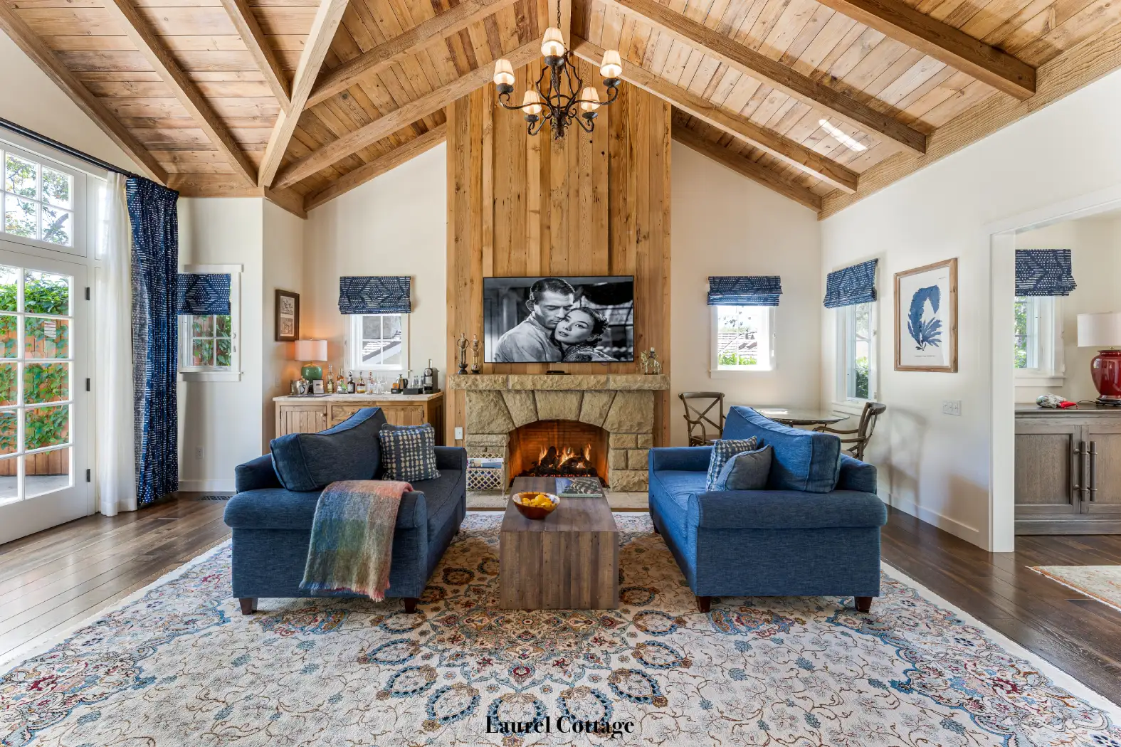Laurel: the living room with its timber-clad fireplace, 2 blue sofas and French doors to the garden.